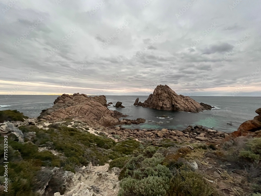 view of small rocky island off coast of ocean in cloudy day view of small rocky island off coast of ocean in cloudy day
