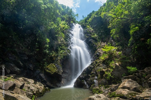 Stunning bride's pool waterfall cascades over a rock-strewn river, surrounded by lush green foliage