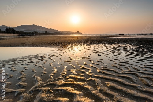 Stunning sunrise captured over a tranquil beach with rolling waves and mountains in background