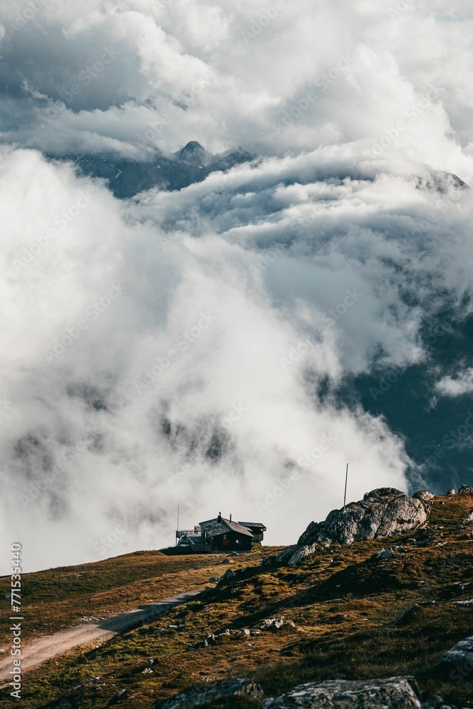 Vertical shot of a house on a mountainside near clouds in the Swiss Alps