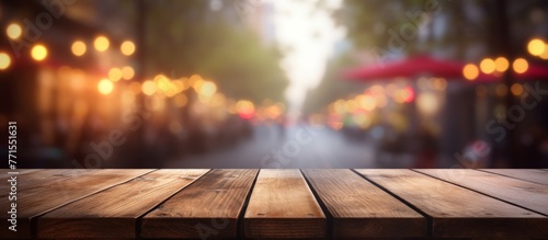 An empty hardwood table sits against a backdrop of a blurred city street. The warmth of the wood contrasts with the cold asphalt road outside, creating a serene landscape