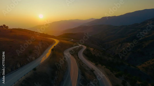 A beautiful aerial view of the curvey road at sunset surrounded by mountain