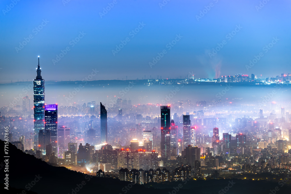 Fototapeta premium A layer of white clouds and mist over Taipei City, together with the city lights, form a colorful glazed light.