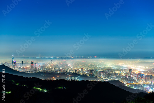 A layer of white clouds and mist over Taipei City, together with the city lights, form a colorful glazed light.