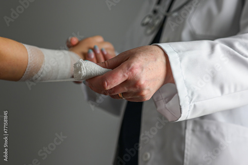 a doctor in a white coat with a stethoscope bandages the hand of a little girl