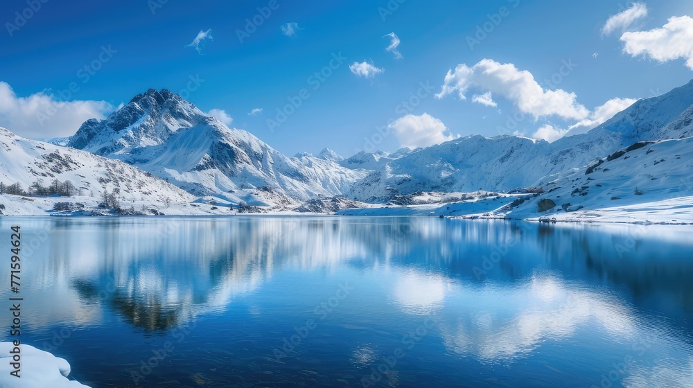 Picturesque scenery of calm lake surrounded by snowy mountains under blue sky in sunny winter day