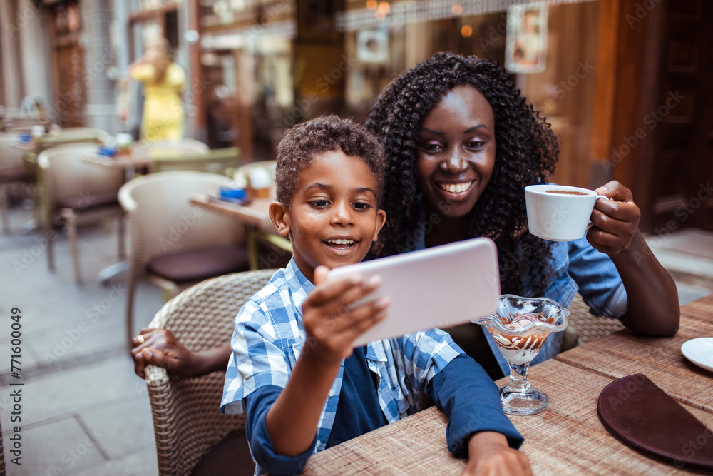 Smiling mother sitting in public cafe with son taking selfie Smiling mother sitting in public cafe with son taking selfie