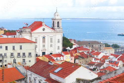View of historical houses with red roofs, Lisbon, Portugal. Amalfa district. The Miradouro de Santa Luzia viewpoint. The Church of Sao Vicente of Fora in the background.