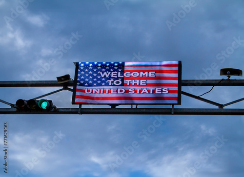 Digital Sign with American Flag stating Welcome To The United States against a cloudy sky.The image was taken at the Otay Mesa Border crossing betwen the USA and Mexico photo