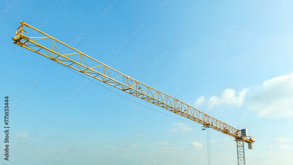 Industrial construction crane with blue sky background at building site - obrazy, fototapety, plakaty 