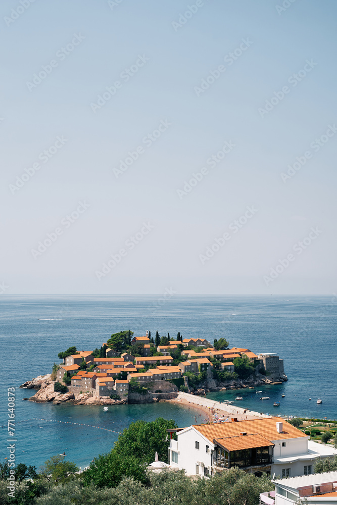 View over the red roofs of old houses to the island of Sveti Stefan. Montenegro