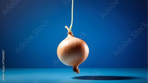 A solitary onion dangling in midair against a vivid blue background. a, solitary, onion, dangling, midair, vivid, blue, background, color image, vegetable, photography, food, organic, garlic, freshnes photo