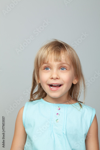 Joyful little girl smiling against a grey background