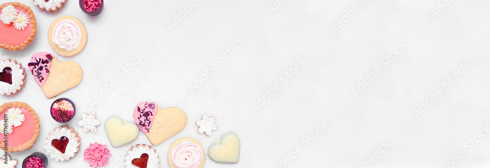 Mothers Day or love themed baking corner border with a variety of cookies and sweet treats. Overhead view on a white marble banner background with copy space. Mothers Day or love themed baking corner border with a variety of cookies and sweet treats. Overhead view on a white marble banner background with copy space.