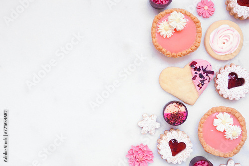 Mothers Day or love themed baking side border with various cookies and sweet treats. Overhead view on a white marble banner background with copy space. © Jenifoto