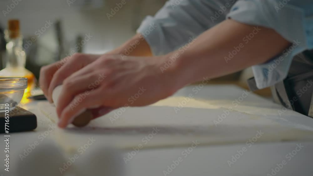 Food. A baker dressed in an apron forms a sheet of dough in an industrial kitchen. Close up of young caucasian man working with dough rolling pin applying innovative baking techniques, puff pastry Food. A baker dressed in an apron forms a sheet of dough in an industrial kitchen. Close up of young caucasian man working with dough rolling pin applying innovative baking techniques, puff pastry
