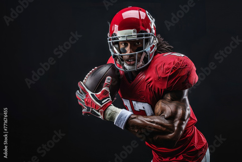 An American football player striking a pose with a ball against a black background