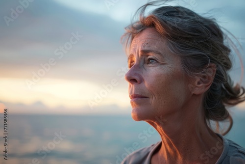 Pensive mature woman facing a window, reflecting on life's challenges © olga_demina