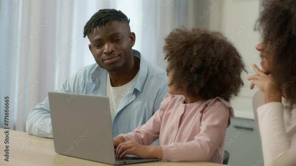 Happy African American smiling family together using laptop at home kitchen talking father little child daughter use computer mother smile kid girl typing pc food delivery application shopping online Happy African American smiling family together using laptop at home kitchen talking father little child daughter use computer mother smile kid girl typing pc food delivery application shopping online