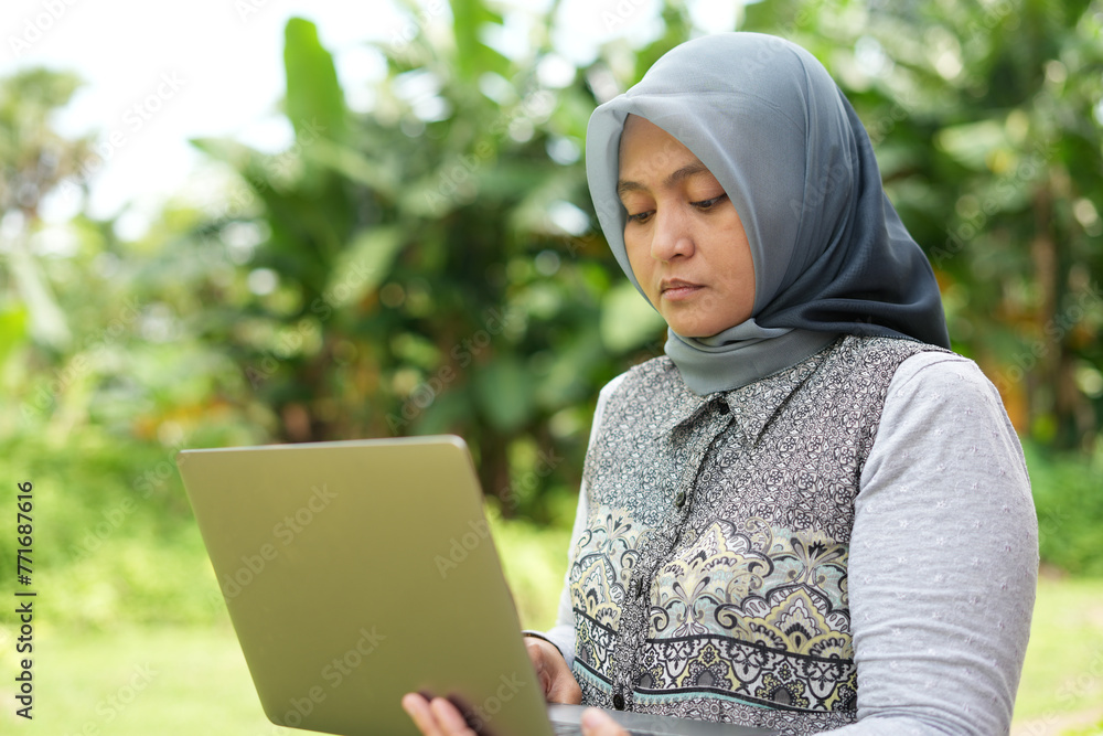 A female entrepreneur is running an online business using a laptop in her hand A female entrepreneur is running an online business using a laptop in her hand