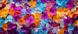 A vibrant array of purple, magenta, and electric blue flowers with delicate petals are scattered on the ground, creating a beautiful artistic pattern at this annual plant event