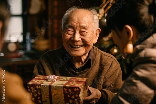 Senior man smiling as he holds a wrapped gift with traditional patterns in a cozy indoor setting