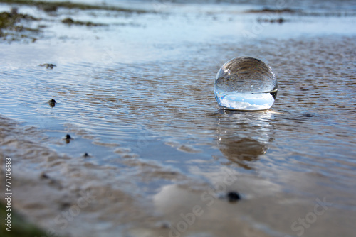 Beach and sea reflected in a sphere lying  in the water