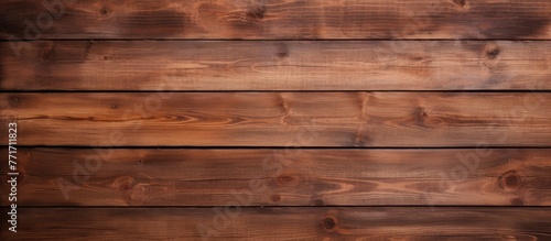 A closeup shot of a brown hardwood plank wall with a rich amber wood stain. The intricate pattern of the flooring material adds warmth to the building