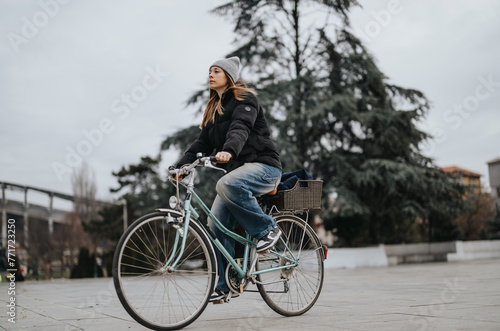 A young adult female rides her vintage bike with a basket through an urban park, capturing the essence of active lifestyle and leisure cycling.