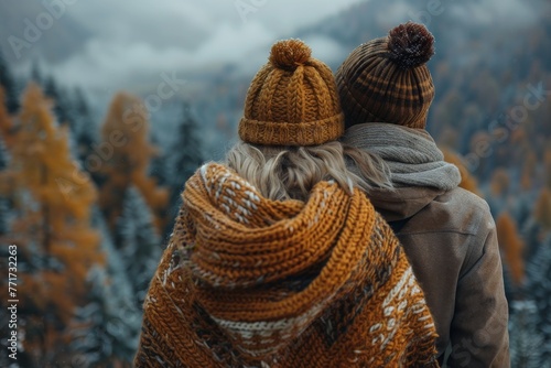 A back view of a couple embracing each other in warm clothing while looking out over a snowy winter landscape, conveying warmth and intimacy