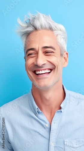 Confident smiling adult man with gray hair on light blue background.