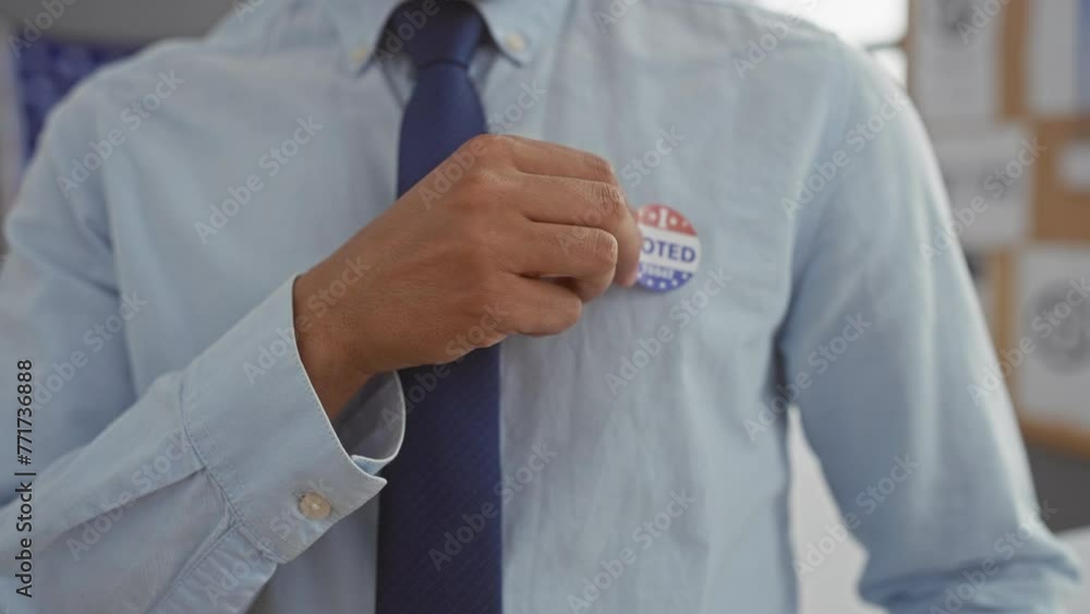 A man in a blue shirt and tie with a 'voted today' sticker at a us polling station A man in a blue shirt and tie with a 'voted today' sticker at a us polling station