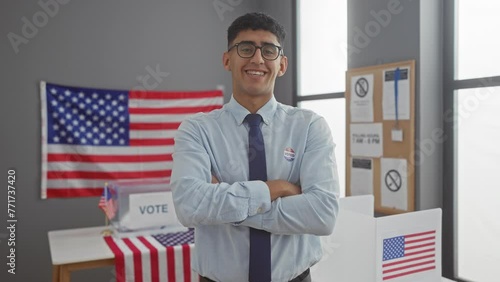 Young man with 'i voted' sticker stands confidently in a polling station with american flags.