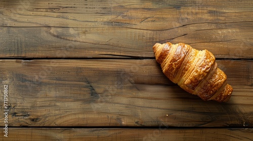 Single croissant on a light wooden surface, minimalistic bakery concept with ample copy space