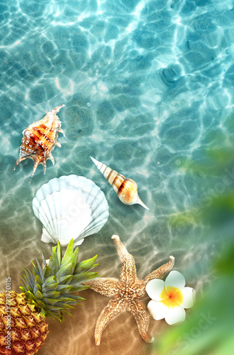 Yellow pineapple, seashells and flowers on a blue water background.