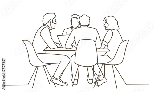 A group of people are sitting around a table, with one person using a laptop