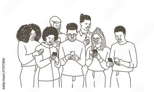 A group of people are standing together and looking at their cell phones