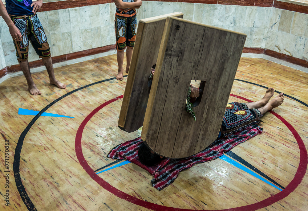 Young man training with sang shields in Zoorkhaneh - traditional Iranian gym in Yazd city, Iran