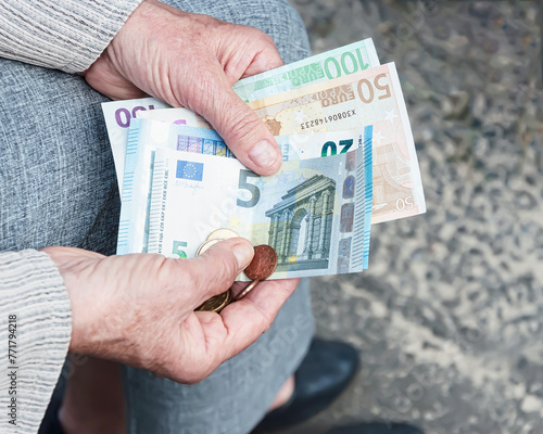 Euro banknotes and coins in the hands of an elderly woman.	