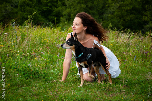 Woman and dog in mountain valley. Landscape of summer nature. Happy girl play with dog in valley outdoor. Carpathians woman with dog. Woman and dog on green grass. Banner
