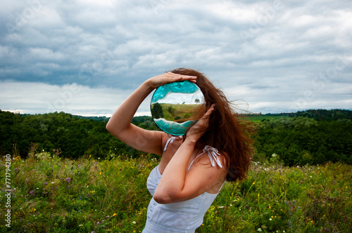 Woman in mountain valley look at mirror. Landscape of summer nature. Beauty girl look at reflection in mirror outdoor. Beauty and sustainability. Carpathians mountain. Woman in valley. Sustainability