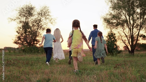 Cheerful team of children, sports games. Child boy, girl play on lawn. Children friends running outdoors in, park. Kids play smiling rejoice. Children have fun running on green grass, meadow. Holiday