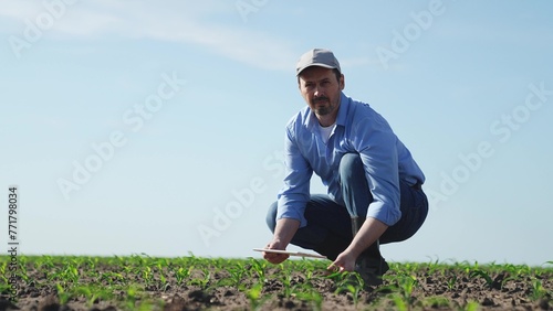 Businessman digital agricultural farmer with tablet. Man male farm worker takes care of corn crops sowing shoots videos takes photos manages resources monitors condition of crop harvest in field.