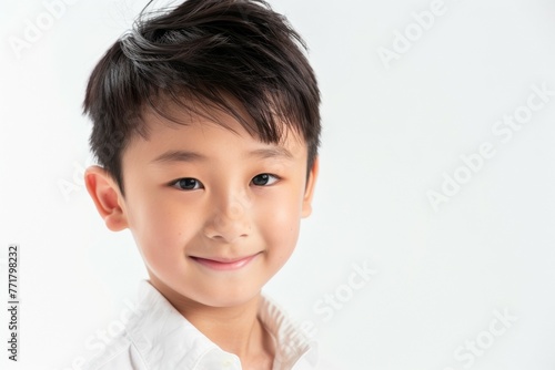 A young boy with short hair and a white shirt is smiling