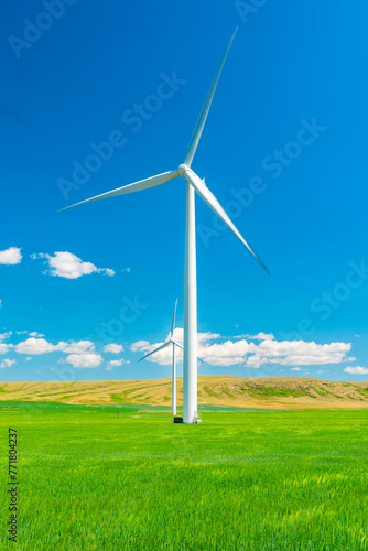 Wind turbine in a summer farm field under a hot blue sky