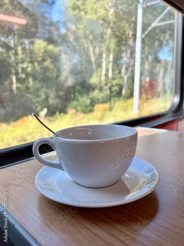 Cup of coffee on a wooden table in front of the window in the train 