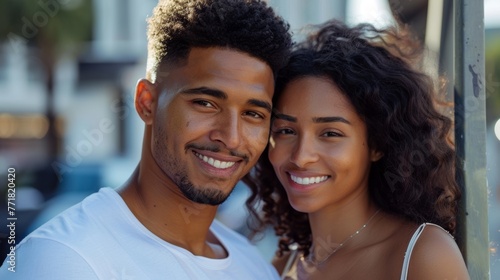 Mixed race couple embracing, smiling, looking at the camera.