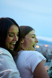Vertical. Smiling young adult millennial multiracial people celebrating meeting on summer night outdoors. Excited group cheerful happy friends gathered together enjoying sunset at rooftop party