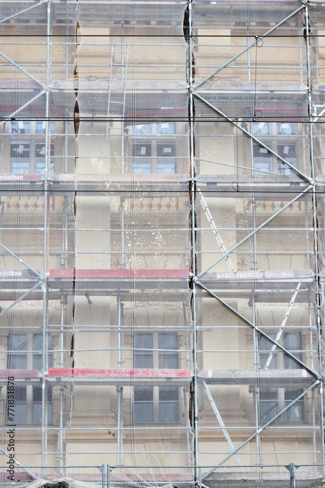 building undergoing renovation, entire facade covered with complex network of scaffolding, obscuring view of its exterior.concepts: building maintenance, construction safety, historic preservation