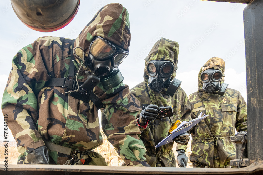 Fototapeta premium Three men in hazmat suits are surveying possible chemical agents.